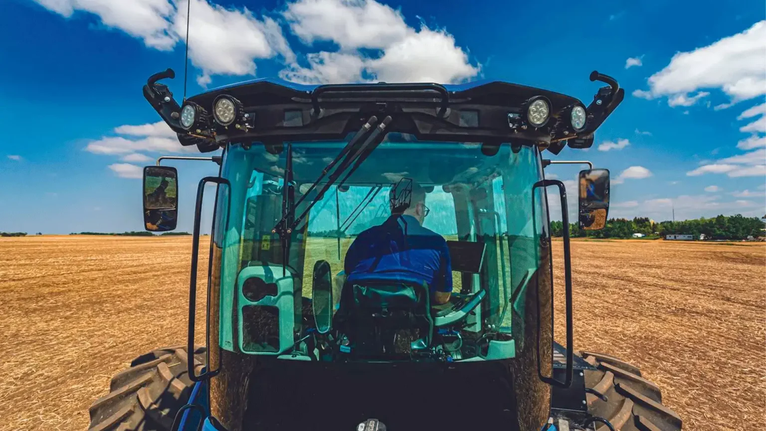 equipamentos_tratores_t9_plm_em_campo_visao_traseira_com_homem_operando_o_trator